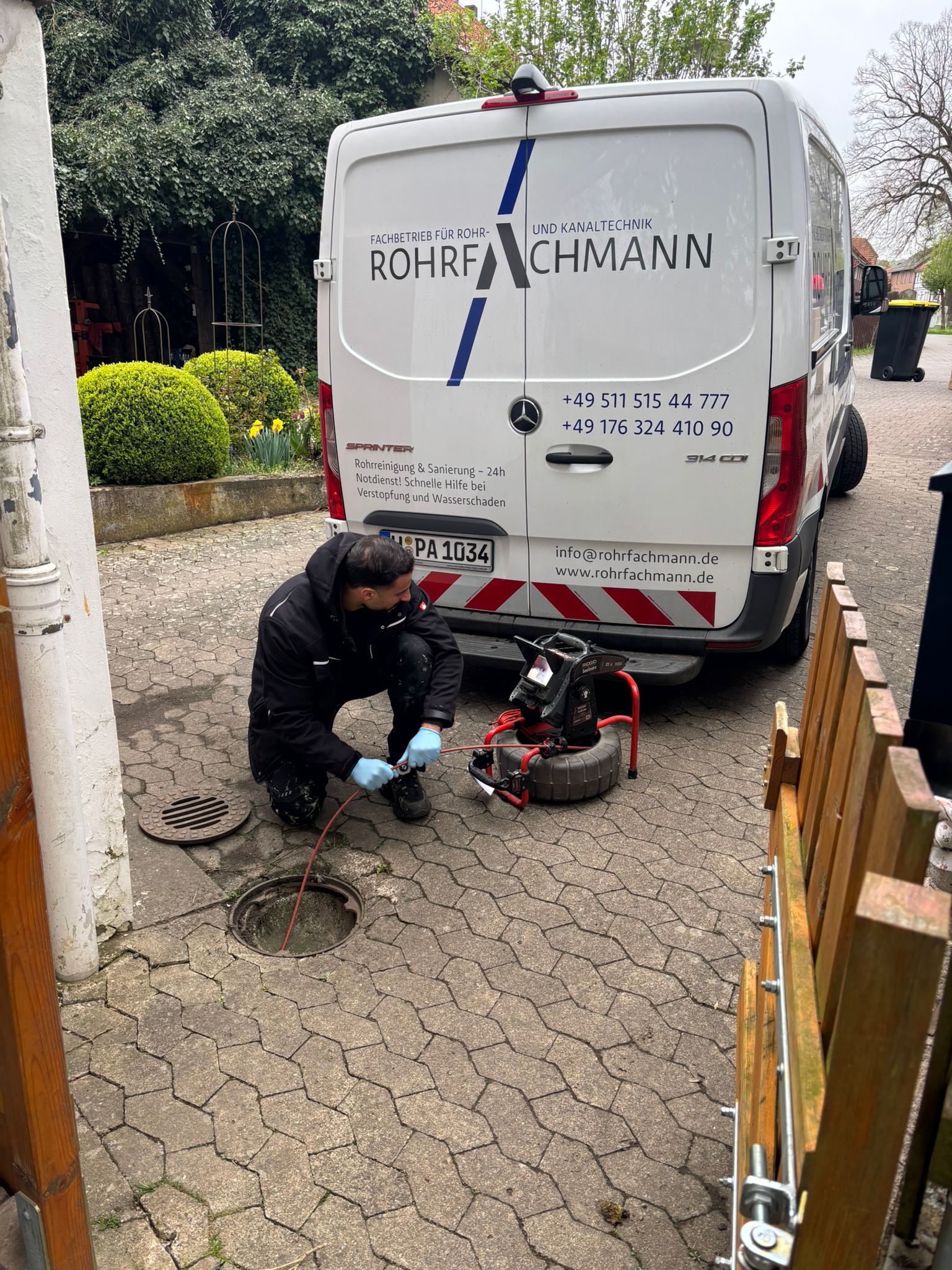 Rohrfachmann bei technischen Arbeiten an einem geöffneten Abwasserschacht