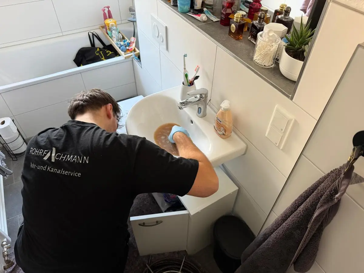 Techniker reinigt einen verstopften Waschbeckenabfluss im Bad